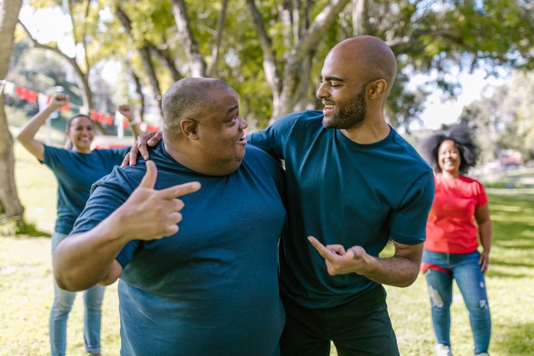 Cheerful friends engaged in a lively team-building exercise in a sunny park setting.