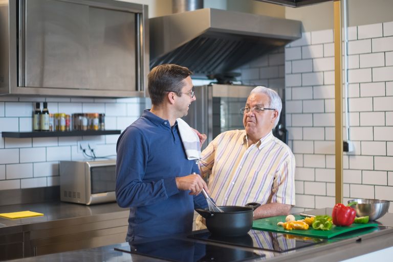Father and son bonding in a modern kitchen while preparing a meal together.