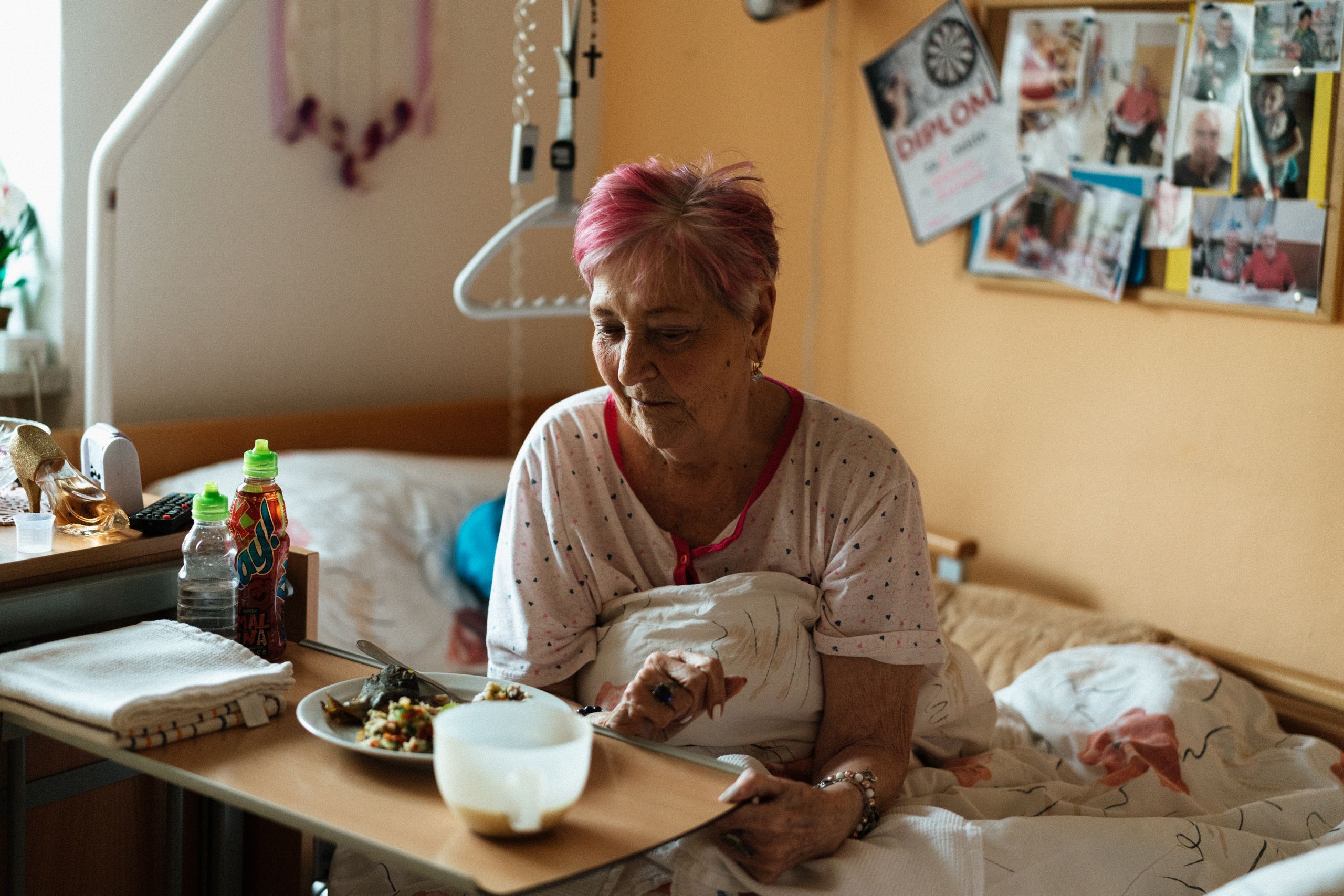 Elderly woman enjoying a meal in a cozy retirement home setting.